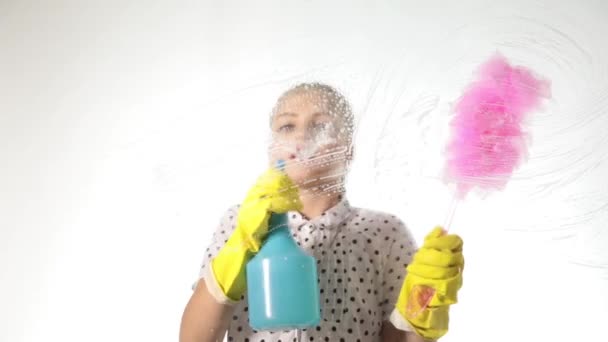 Glimlachend kleine huisvrouw gewassen het raam met een spray, doek en wasmiddel. Groot glas in schuim. Huiswerk concept. — Stockvideo