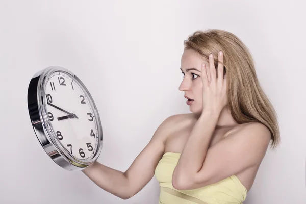 Beautiful young woman looking at a large silver retro clock that she is holding, she wonders how much time passed — Φωτογραφία Αρχείου