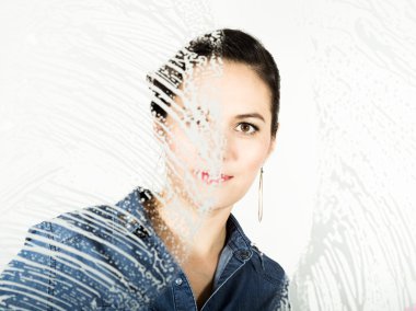 bir sprey, kumaş ve deterjan ile pencere yıkanmış genç ev hanımı. Köpük büyük bardakta. Ev kavramı.