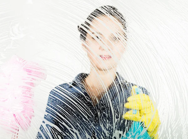 Junge Hausfrau gewaschen Fenster mit einem Spray, Tuch und Spülmittel. großes Glas in Schaumstoff. Hausaufgabenkonzept. — Stockfoto