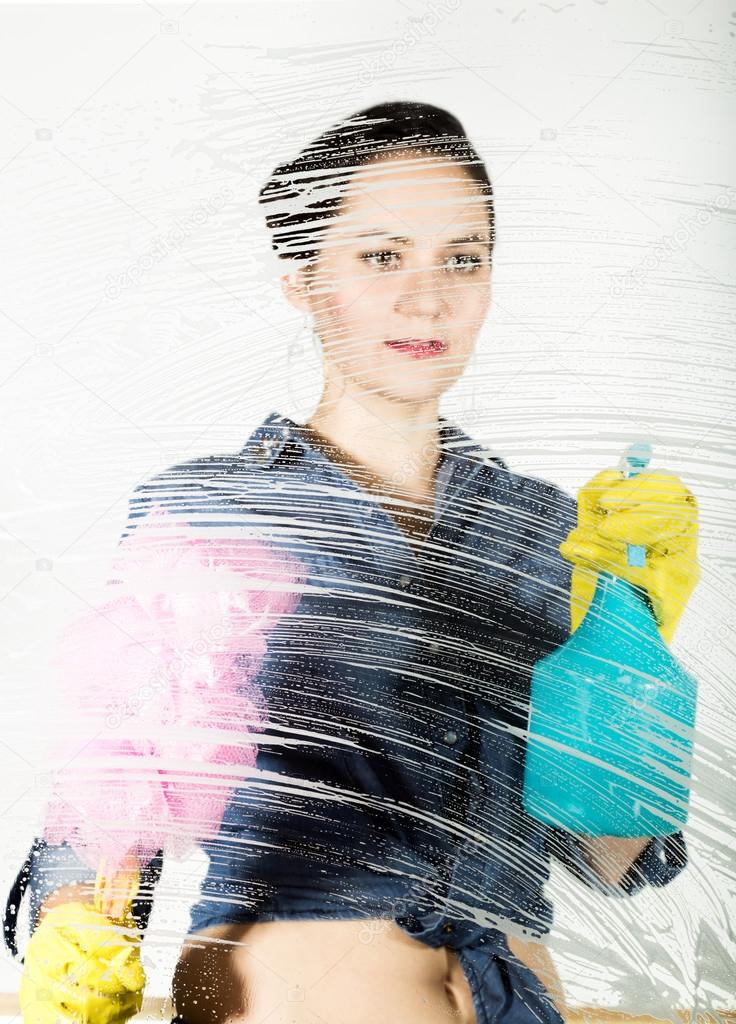 young housewife washed window with a spray, cloth and detergent. Large glass in foam. Housework concept.