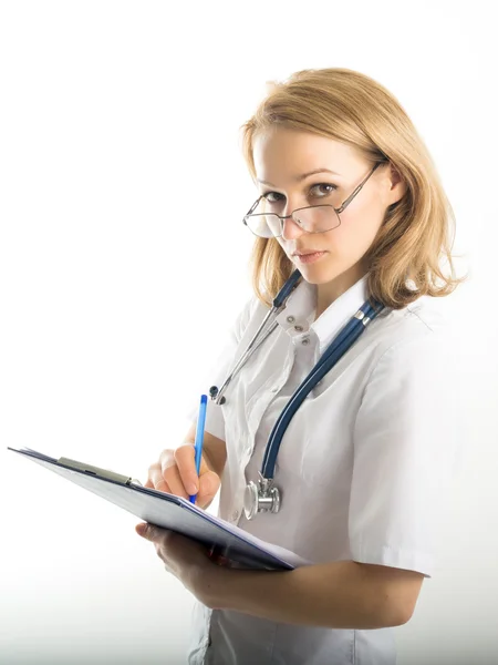 Schöne junge Ärztin in medizinischem Gewand und Gummihandschuhen mit einer Krankenakte. Krankenschwester macht Einträge in Krankenakte — Stockfoto