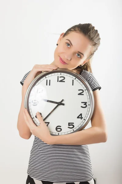 Beautiful young woman looking at a large silver retro clock that she is holding, she wonders how much time passed — Stockfoto