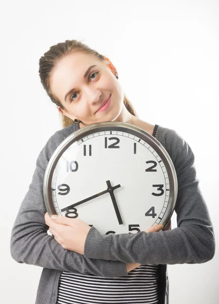Beautiful young woman looking at a large silver retro clock that she is holding, she wonders how much time passed — ストック写真