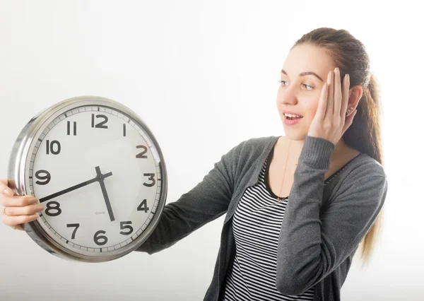 Beautiful young woman looking at a large silver retro clock that she is holding, she wonders how much time passed — Stockfoto