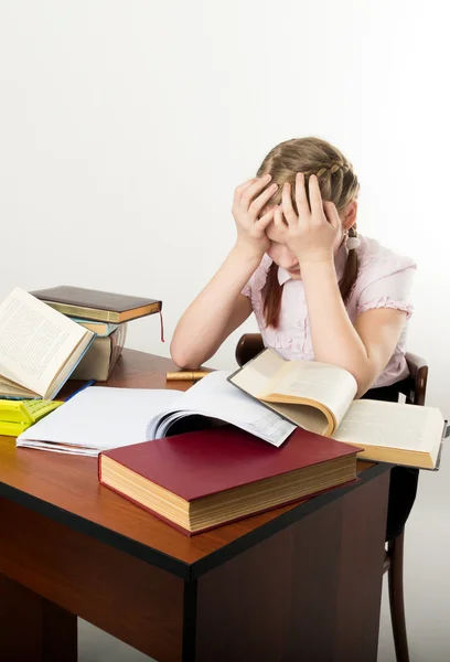 Tiener meisje zitten aan een tafel voor haar grote stapel boeken. schoolmeisje lezen van een boek en huiswerk — Stockfoto