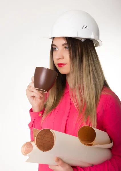 Krásná žena stavební inženýr drží plány. mladá žena architekt pití kávy z hnědé pohár — Stock fotografie