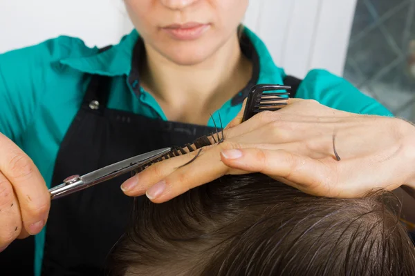 Salon fryzjerski ścina włosy nożyczkami na koronę. przystojny zadowolony klient w profesjonalny salon fryzjerski — Zdjęcie stockowe