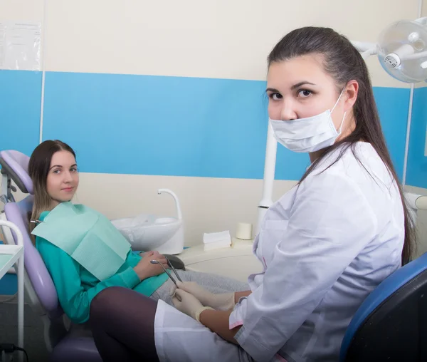 Fiatal nő látogató fogorvos fogászati klinikán. Orvos megvizsgálja a szájüregben a fogszuvasodás. — Stock Fotó