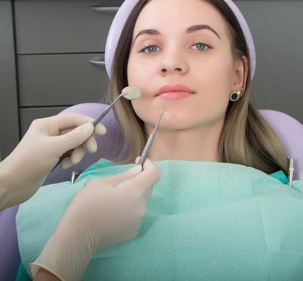 Mujer joven visitando dentista en clínica estomatológica. El médico examina la cavidad oral en la caries dental . — Foto de Stock