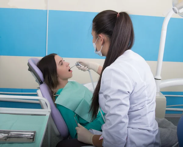 Mujer joven visitando dentista en clínica estomatológica. El médico examina la cavidad oral en la caries dental . — Foto de Stock