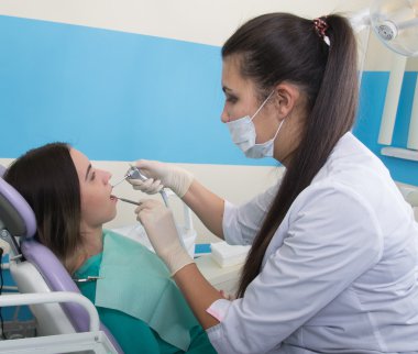 Genç kadın dişçi klinikte ziyaret dişçi. Doktor diş çürüğü sözlü den inceliyor.