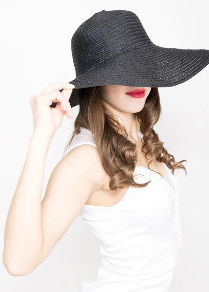 Hermosa mujer delgada sexy en un pequeño vestido blanco y amplio sombrero negro — Foto de Stock
