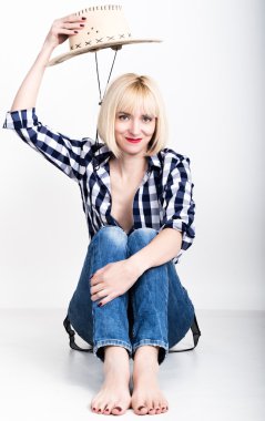 Young beautiful sexy woman in a plaid shirt jeans and a cowboy hat