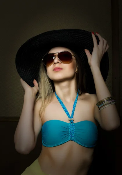Beautiful young lady in a bathing suit, big black hat on high heels, and sunglasses — Stock Photo, Image
