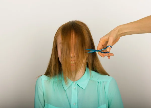 Красивая молодая рыжая девушка в парикмахерской делает высушивание, стрижку челки, полировку волос — стоковое фото