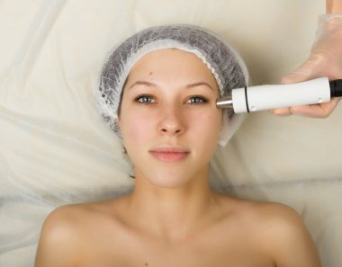 Beautician examining the face of a young female client at spa salon. getting rf-lifting in a beauty salon. Professional consultation