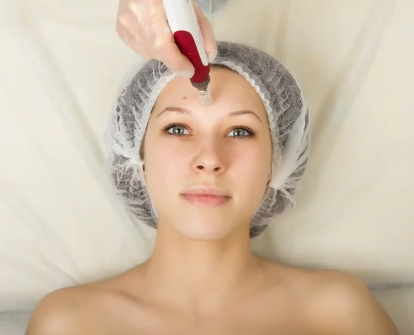 Beautician examining the face of a young female client at spa salon. fractional mesotherapy in a beauty salon. Professional consultation — Stock Fotó