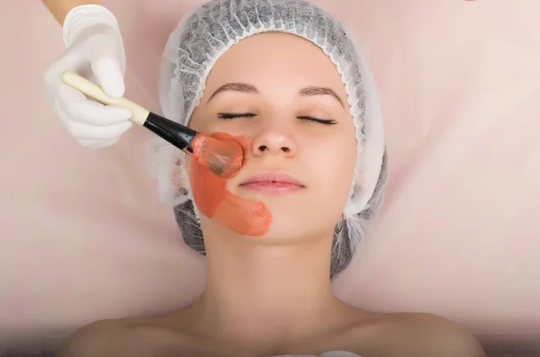 Beautician examining the face of a young female client at spa salon. beautician does cosmetic mask on the patients face. Professional consultation — Stock Photo, Image