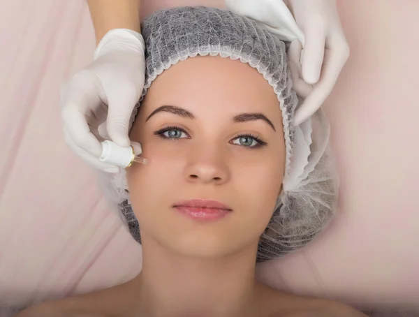 Esteticista examinando o rosto de uma jovem cliente no salão de spa. esteticista remove a máscara facial do paciente. Consulta profissional — Fotografia de Stock