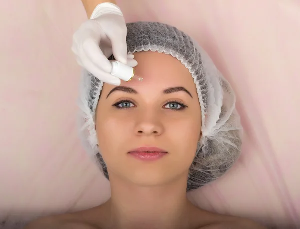 Kozmetikus megvizsgálja az arcát egy fiatal női ügyfél a spa szalon. kozmetikus eltávolítja a betegek álarc. Szakmai konzultáció — Stock Fotó