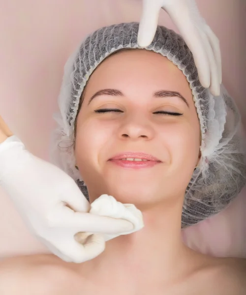 Kozmetikus megvizsgálja az arcát egy fiatal női ügyfél a spa szalon. kozmetikus eltávolítja a betegek álarc. Szakmai konzultáció — Stock Fotó