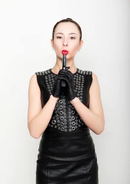 Сексуальная молодая женщина в черном кожаном платье с плетеными волосами держит пистолет — стоковое фото