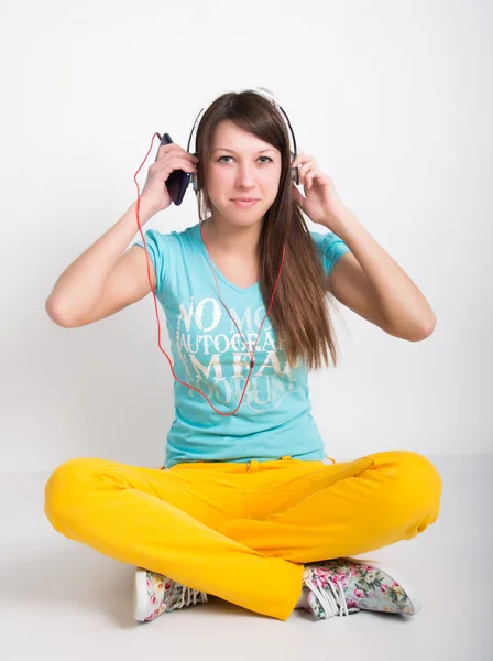 Adolescente en pantalon jaune, écoutant de la musique depuis votre smartphone — Photo