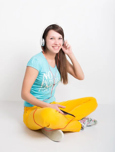 Adolescente en pantalones amarillos, escuchando música desde su teléfono inteligente — Foto de Stock