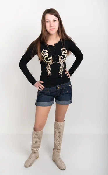 Menina em calções jeans, t-shirt com mangas compridas e botas — Fotografia de Stock
