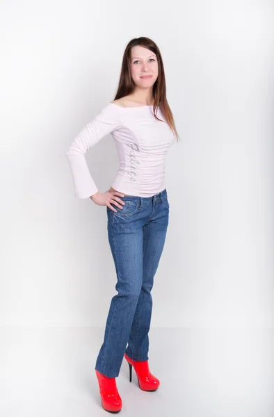 Bela menina magro em calças jeans e sapatos de salto alto vermelho e t-shirt — Fotografia de Stock