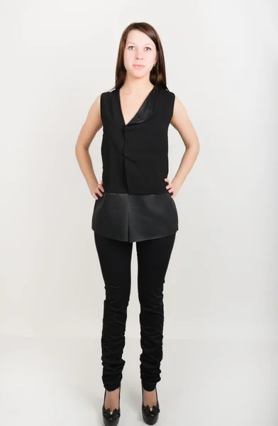 Mooi slank meisje in een zwarte broek en een zwarte zonder mouwen blouse — Stockfoto