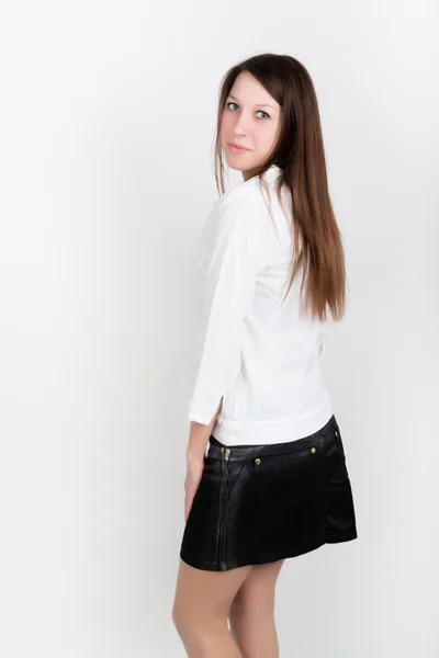 Menina fina bonita em uma saia preta curta e blusa branca, posando — Fotografia de Stock