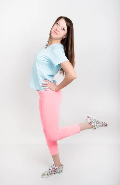 Bela menina atlética esbelta em leggings rosa, um top de tanque azul e tênis coloridos — Fotografia de Stock