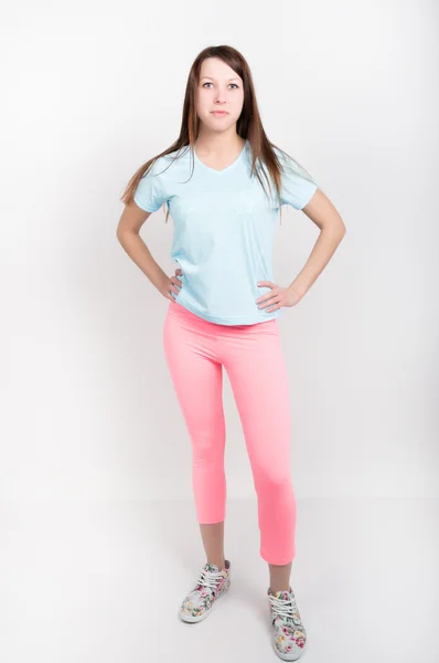 Piękna dziewczyna szczupła lekkoatletycznego w różowe legginsy, niebieski podkoszulek i kolorowe trampki — Zdjęcie stockowe