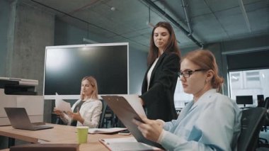 İş ekibi, ortak bir toplantı sırasında modern ofis ortamında belgeleri tartışıyor