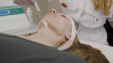 Uzman kozmetoloji teknikleri, kalıcı makyaj uygulaması için bir kadının teninde ağır çekimde sergilenmiştir.