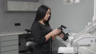 Diş hekimliği uzmanı, modern bir klinikte hasta tedavisi ve prosedürleri için ekipman hazırlar.