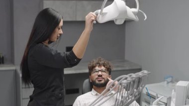 Dişçi, modern klinik ortamında hastayı hijyenistle birlikte tedaviye hazırlıyor.