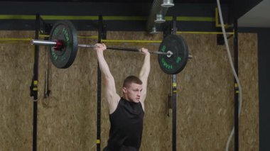 Spor salonunda ağır çekimde ağırlık kaldırma eğitimi.