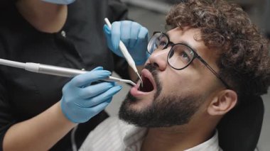 Diş hekimi klinikte diş temizliği yapıyor. Ağız sağlığı için aletler ve teknikler kullanıyor.