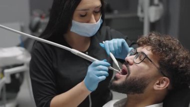 Diş hekimi klinikteki hastayı diş kontrolü için alet ve ekipmanla tedavi ediyor.