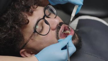 Diş hekimi, dişçi randevusunda diş bakımı ve diş temizleme araçları kullanarak klinikte bir hastayı tedavi eder.