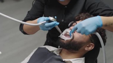 Erkek klinikte diş tedavisi görüyor ve kadın dişçi tedavi görüyor.