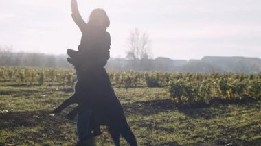 Köpek ve eğitmen güneşli bir günde tarlada kovalamaca oynuyorlar.