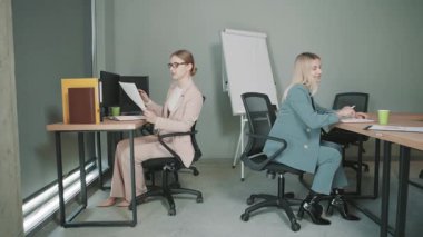 Meslektaşlar, işyerlerindeki görevler ve iletişim konularına odaklanarak ofiste birlikte çalışırlar.