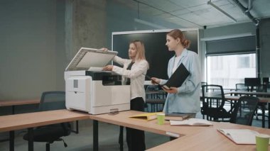 Ofis ekibi yoğun çalışma saatlerinde fotokopi makinesi etrafında iş birliği yapar.