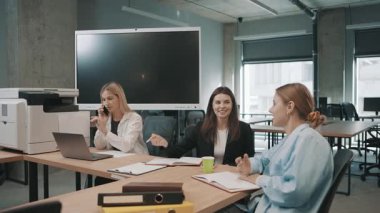 Takım üyeleri proje güncellemelerini tartışıyor ve öğleden sonraki bir çalışma toplantısında modern bir ofis alanında fikirlerini paylaşıyorlar.