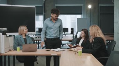 Takım üyeleri proje detaylarını çalışma saatlerinde modern ofis alanında tartışırlar