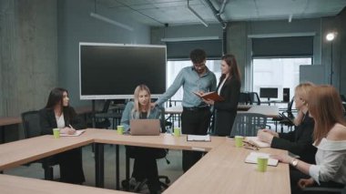 Takım üyeleri, modern bir tasarım ile bir ofis ortamında yaptıkları toplantıda proje görevlerini ve fikirlerini tartışırlar.